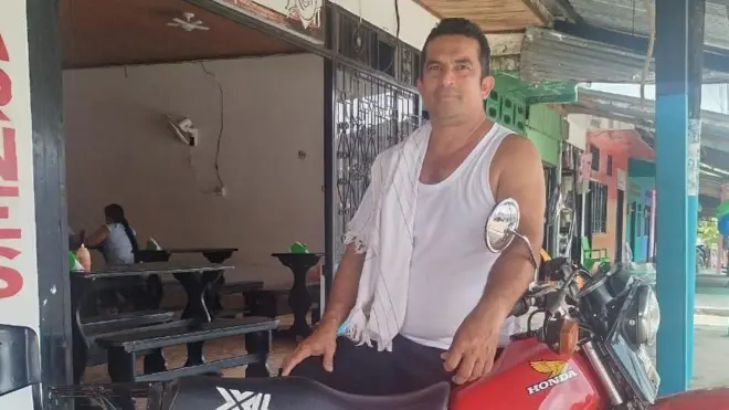 Johan con una camiseta manga sisa, y su moto. 