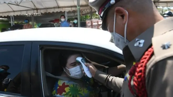 เจ้าหน้าที่ตำรวจวัดอุณหภูมิผู้ขับขี่ที่จุดคัดกรองควบคุมการแพร่ระบาดของโควิด-19 บริเวณ ถ.ราชพฤกษ์ เขตตลิ่งชัน รอยต่อกับ จ.นนทบุรี