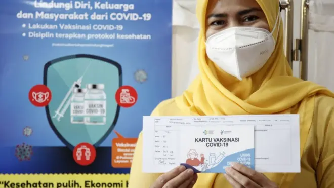 Seorang perempuan menunjukkan kartu vaksinasi setelah mendapat vaksin Covid-19 di Jakarta.