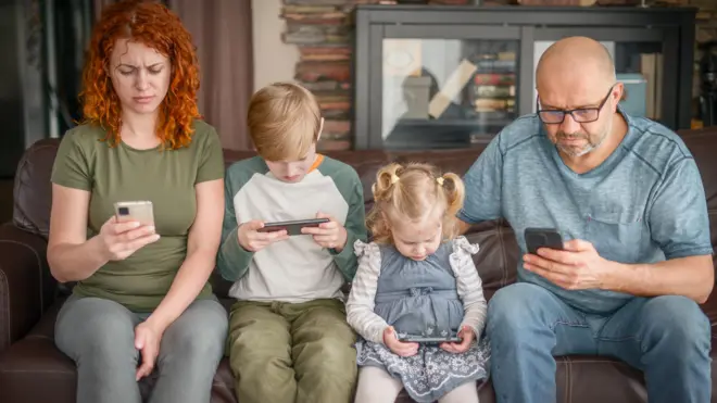 Rodzina korzystająca z telefonów w domu.