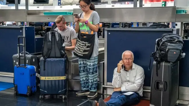 Tiga orang turis menunggu kepastian keberangkatan dari bandara Hong Kong setelah unjuk rasa pro-demokrasi sempat mendudukinya.