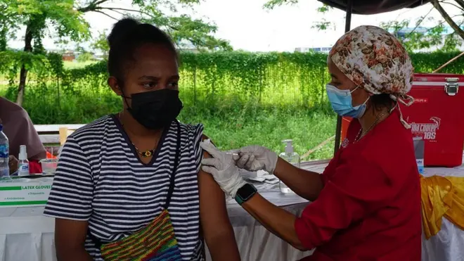 Petugas menyuntikan vaksin Covid-19 kepada wraga di gerai vaksinasi di Taman Sorong City depan Bandara DEO Kota Sorong, Papua Barat, Senin (13/12/2021).