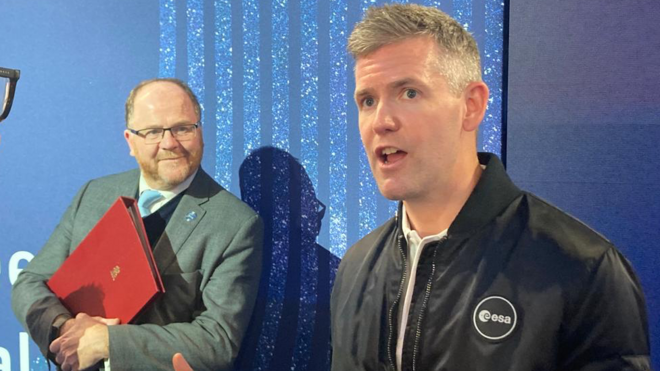 John McFall falandoslots que pagam de verdadeambiente interno, observado por outro homem