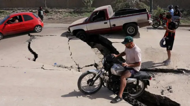 Um homem de motocicleta passa por estrada danificada após terremotos atingirem a Venezuela