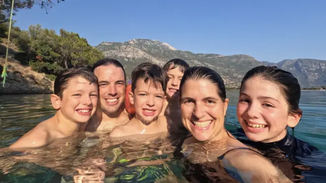 La familia posa bañándose entre montañas en uno de sus viajes.