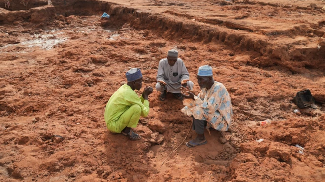 Group of men dey pray for those wey die for wia pesin house dey before. Dem bend down.
