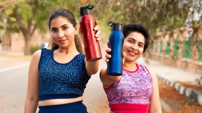 నీళ్ల బాటిళ్లు చూపిస్తున్న మహిళలు