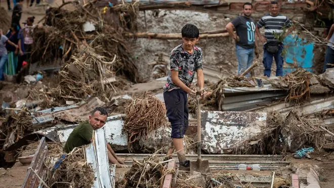 Personas con palas buscan entre los escombros.