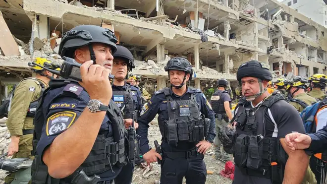 İsrail güvenlik güçleri ve ilk müdahale ekipleri, Tel Aviv'deki Ramat Aviv bölgesindeki bir yerleşim bölgesindeki müdahaleyi koordine ediyor. Bir kişinin elinde telsiz var.