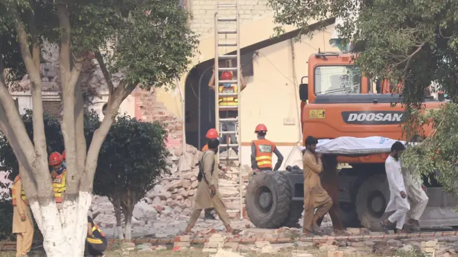 يحرك الناس جثة أحد الضحايا في موقع الضربة الصاروخية الهندية في موريدكي، إقليم البنجاب، باكستان.