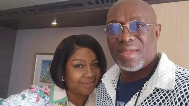 Iyawo Adewale Ayuba, , Azukaego Kwentoh ati gbajumọ olorin Fuji naa ree ninu aworan yii. Wọn so mọ ara wọn, wọn si n rẹrin-in muse. Adewale Ayuba lo igo soju, o wọṣọ funfun to ni iho, o si wọ alawọ eeru sinu pẹlu ṣeeni to fi sọrun. Iyawo rẹ ṣerun oniwiigi, o lo yẹti, o si wọṣọ alawọ funfun ati awọ ere to ni pupa diẹ.