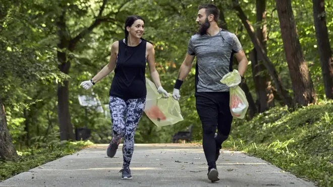 Un hombre y una mujer practicando plogging en un bosque