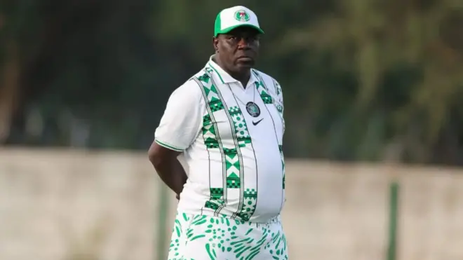 Magudu, akọnimọ-ọn-gba ẹgbẹ agbabọọlu Super Falcons ti wọn jawe gbele ẹ fun ree, pẹlu aṣọ ati fila ẹgbẹ agbabọọlu Naijiria, o ka ọwọ rẹ mejeeji sẹyin, to si n woye pẹlu ironu to gba ọkan rẹ.
