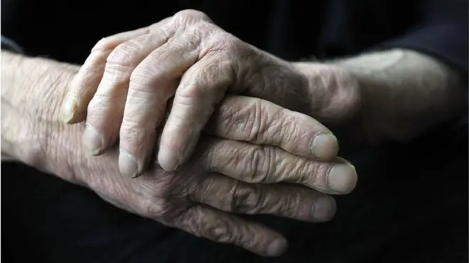 Elderly male rubbing his hands together