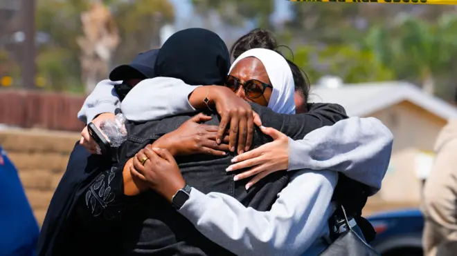 يعانق أشخاص بعضهم بعضاً قرب موقع الهجوم في سان دييغو بولاية كاليفورنيا، الاثنين 18 مايو/أيار 2026، بعد إطلاق نار أمام المركز الإسلامي في المدينة أسفر عن مقتل خمسة أشخاص، من بينهم المشتبه بهما المراهقان. وقالت الشرطة إن حارس أمن في المركز كان بين القتلى الذين سقطوا خارج المبنى صباح الاثنين.