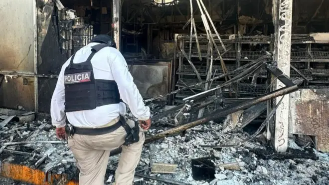 A police officer walking through the rubble of a burnt out building