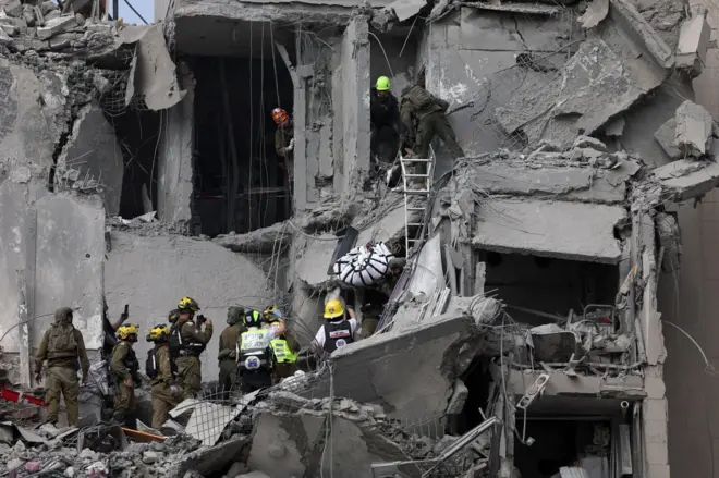 Prédio destruído em Israel, com equipes de resgate