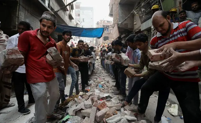 मुस्ताफाबाद इलाक़ेै में बचाव अभियान में मदद करते लोग