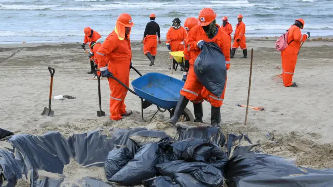 Un equipo de trabajadores limpian las manchas de alquitrán de las playas a lo largo de la orilla del mar en México.