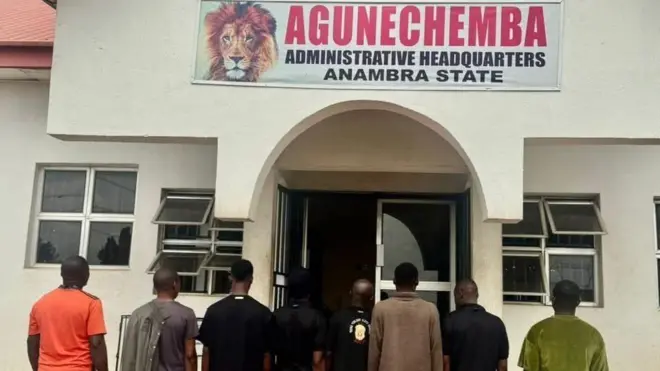 Eight men stand for front of building