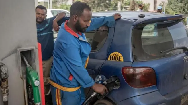 ቪትዝ መኪና ላይ ነዳጅ የሚቀዳ የነዳጅ ማደያ ሠራተኛ