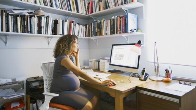 Mulher grávida trabalhando diante do computador