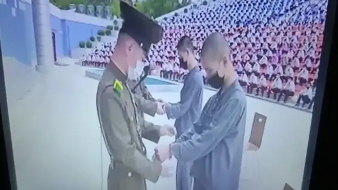 북한 보위부원들이 두 소년에게 수갑을 채우고 있다