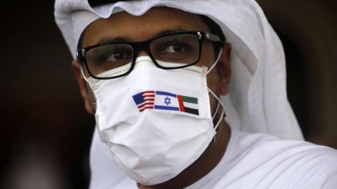 رجل يرتدي كمامة عليها علم إسرائيل والإمارات والولايات المتحدة