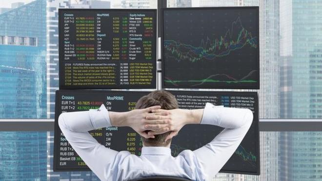 Inversor mirando sus acciones desde su oficina en un rascacielos