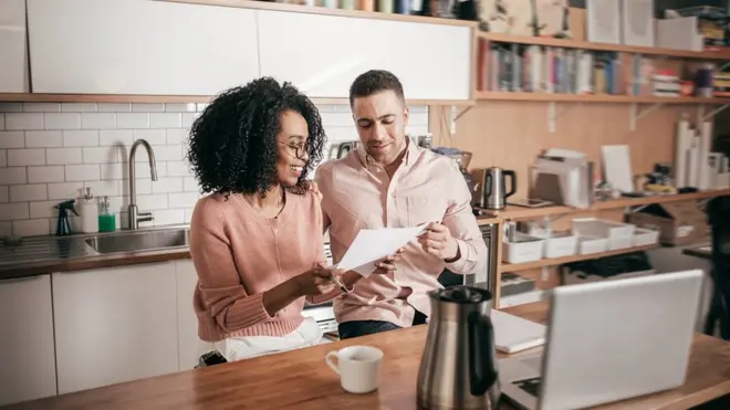 Couple dey look bills for front of computer