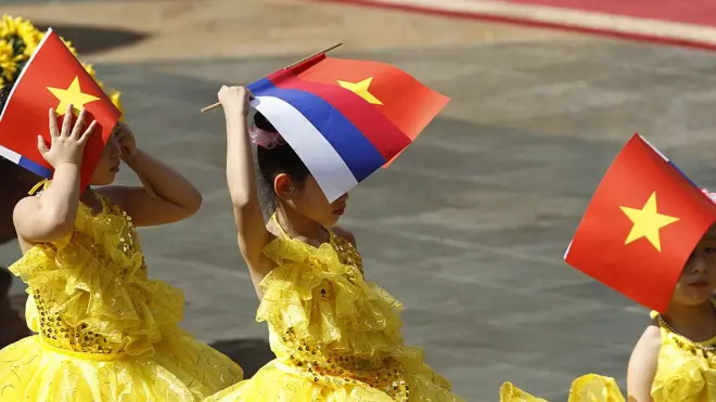 Các em nhỏ lấy cờ Việt Nam và Nga che nắng khi chờ Tổng thống Vladimir Putin đến thăm hồi tháng 11/2018