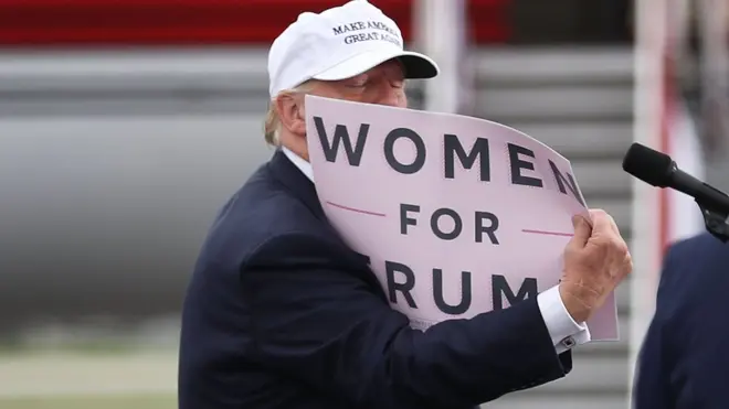 Donald Trump con un cartel que dice "Mujeres por Trump".