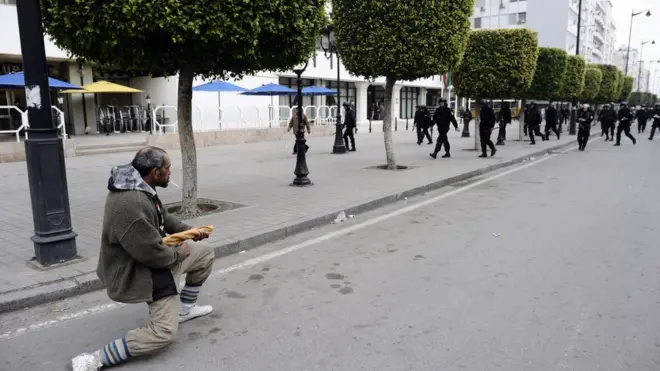 رفع المتظاهرون في تونس الخبز للتعبير عن تفشي الفقر و الفساد خلال فترة حكم بن علي