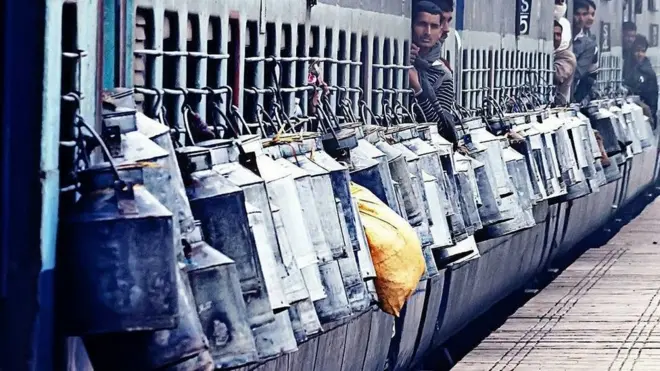 రైలు బయట కిటికీలకు కట్టిన పాల క్యాన్లు