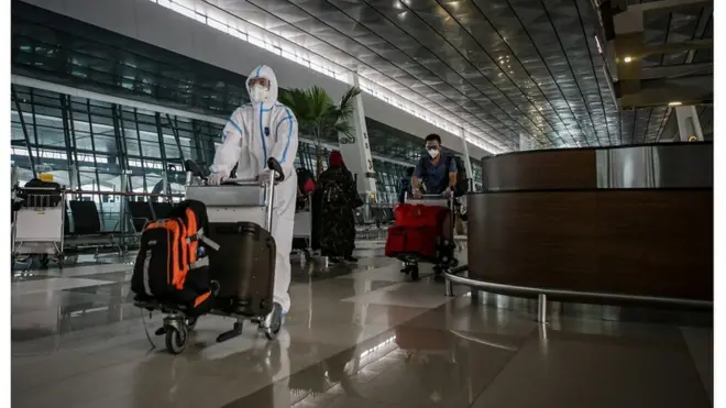 Seorang penumpang pesawat menggunakan baju hazmat berjalan di Terminal 3 Bandara Internasional Soekarno Hatta, Tangerang, Banten, Senin (5/7/2021).