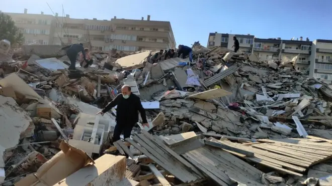 A man walks among debris of collapsed buildings in Izmir