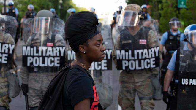 Black woman in front of police in riot gear