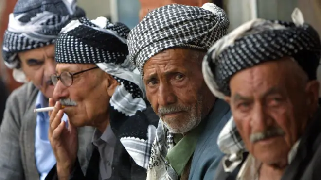 Elderly Iraqi Kurdish men in traditional Kurdish garb sit in the bazaar of Suleimaniyeh, the Patriotic Union of Kurdistan (PUK)-controlled city, some 340km northeast of Baghdad, 17 October 2002