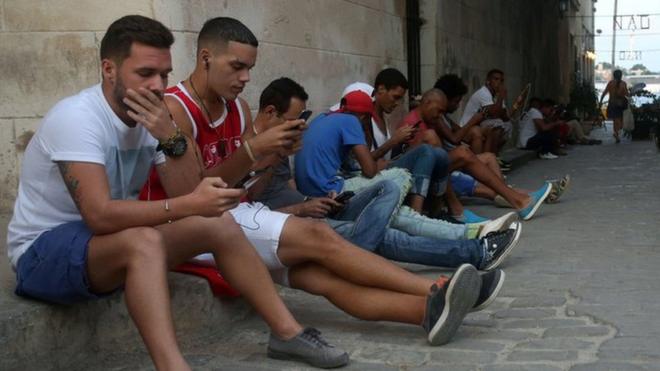 Personas conectándose a Internet a través de sus teléfonos celulares en La Habana.
