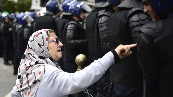 Пожилая женщина разговаривает с полицейскими алжирских спецподразделений во время недавних протестов