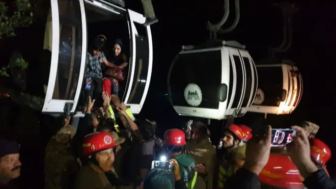 ریسکیو اہلکار کیبل کار میں پھنسے ایک خاندان کو باہر نکال رہے ہیں۔
