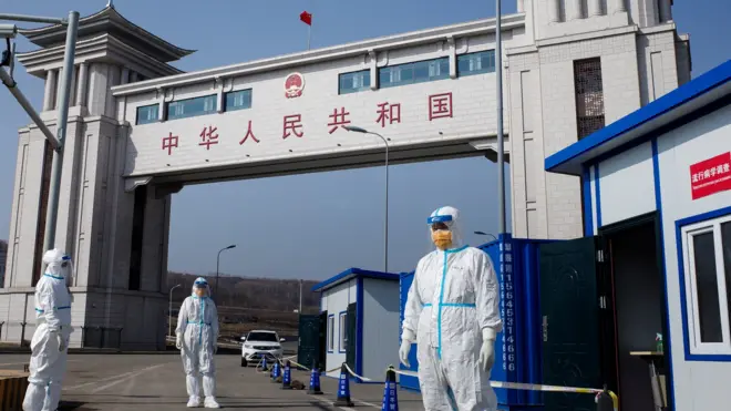 This photo taken on May 1, 2020 shows staff wearing hazmat suits as a precaution against the COVID-19 coronavirus waiting to check a truck at a customs checkpoint on the border with Russia at Suifenhe, in China's northeast Heilongjiang province.