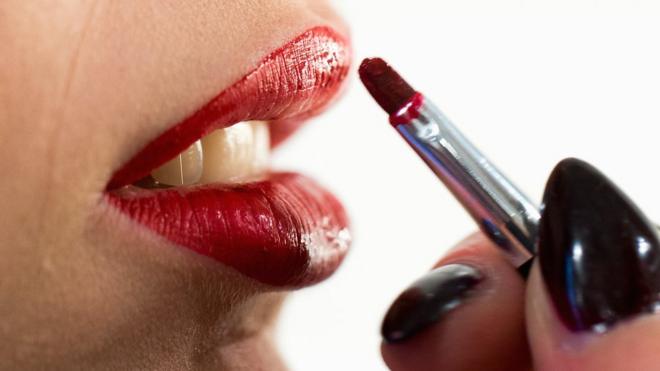 Woman applying bright red lipstick