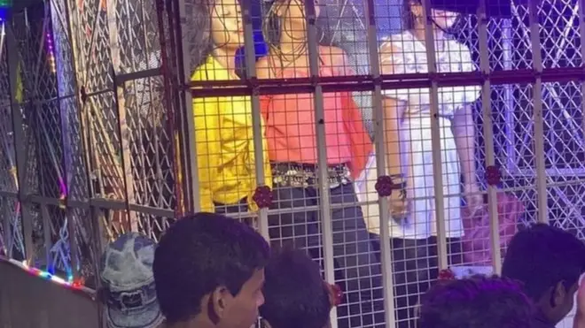 پنجرے میں رقص کرتی لڑکیاں اور ان کے ساتھ ہجوم