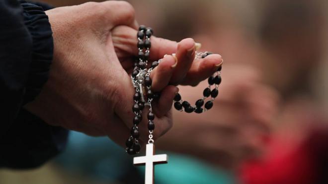 Persona rezando con un rosario en la mano