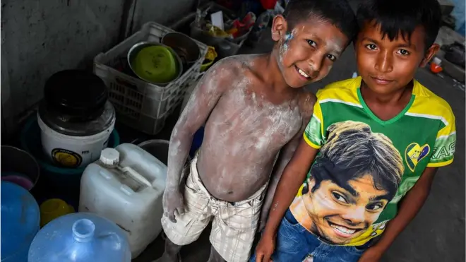 पानी के खाली पीपों के साथ स्थानीय बच्चे