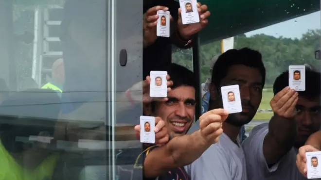 File photo of asylum seekers holding up identity cards after landing in Manus island in Papua New Guinea