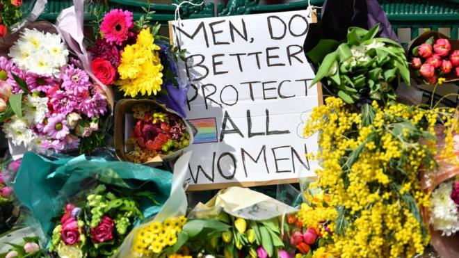 Flowers and a sign that reads "Men, Do Better. Protect All Women" in memory of Sarah Everard on Clapham Common, London, on 13 March 2021