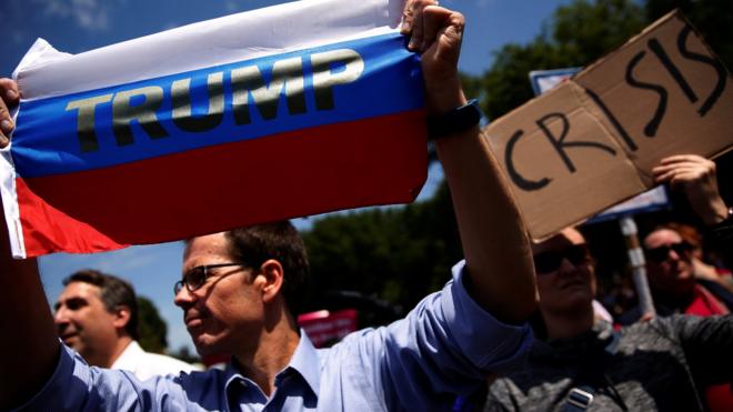 A protester holds a Russian flag with President Donald Trump's name on it as demonstrators rally outside the White House