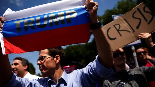 A protester holds a Russian flag with President Donald Trump's name on it as demonstrators rally outside the White House